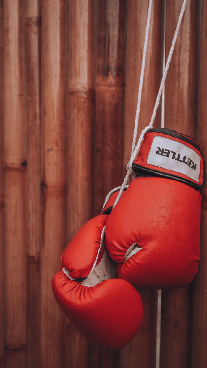 Striking red boxing gloves on a wooden background, symbolizing strength and determination.